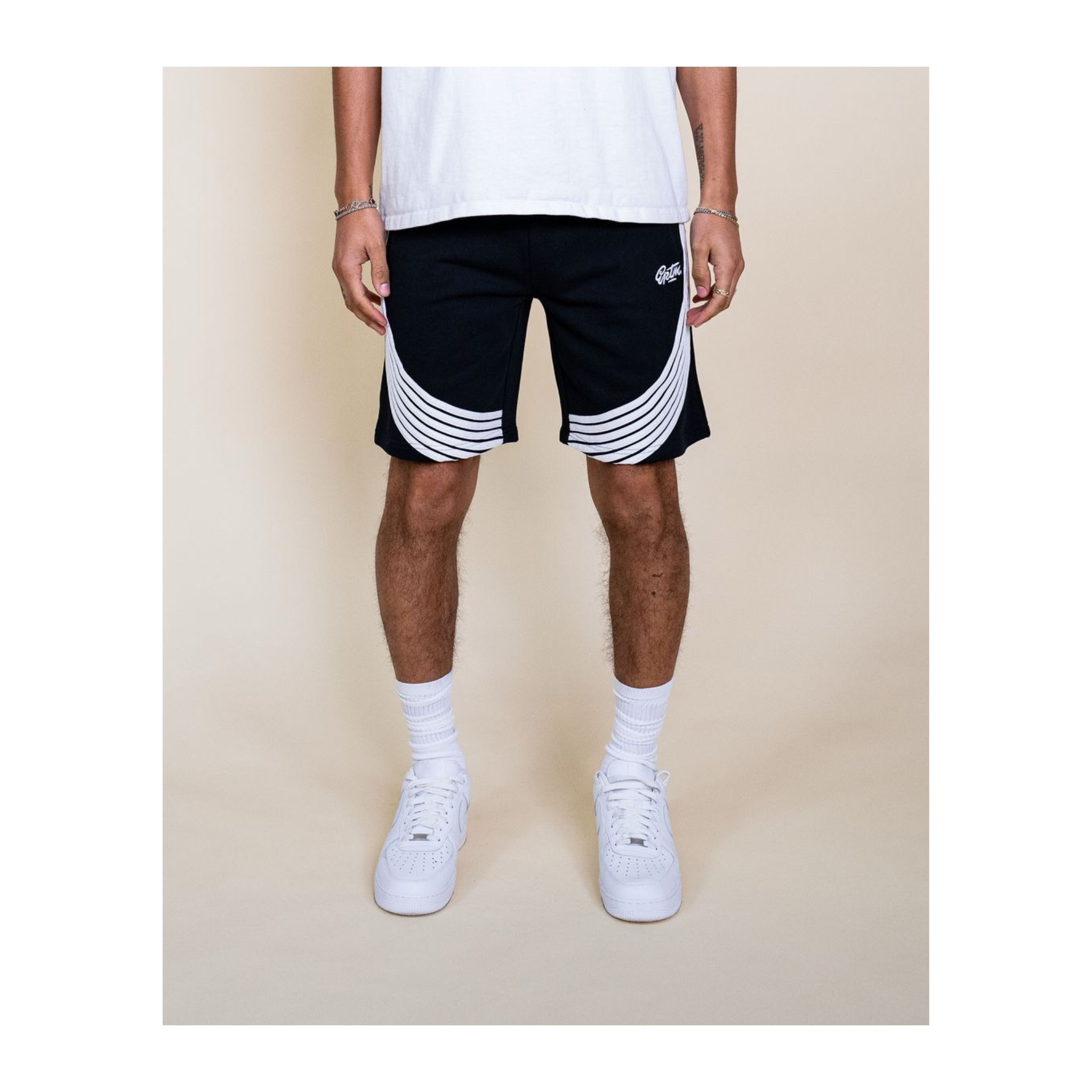 Person wearing black shorts with white stripes on a beige background